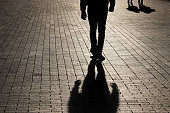 Silhouette and shadow of a lonely man walking walking towards a couple on a street