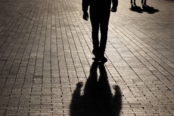 silhueta e sombra de um homem solitário caminhando em direção a um casal em uma rua - violence black men women - fotografias e filmes do acervo
