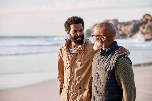 Father and son, best buds for life Shot of a young man going for a walk along the beach with his father adult offspring photos stock pictures, royalty-free photos & images