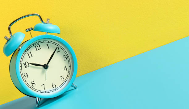 istock Alarm clock on turquoise yellow background. 1201599914