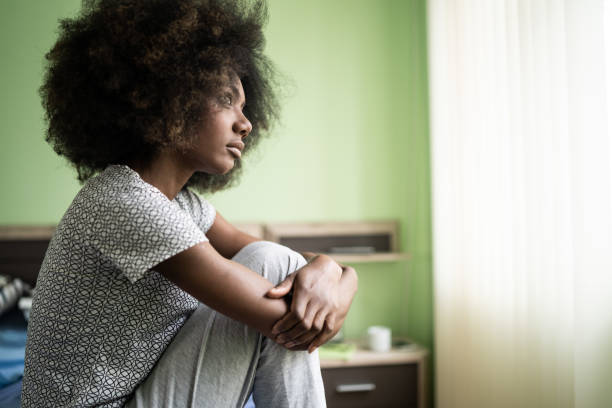 istock Sad afro woman sitting on a bed 1201604392