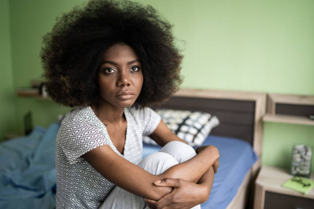 istock Sad afro woman sitting on a bed 1201604394