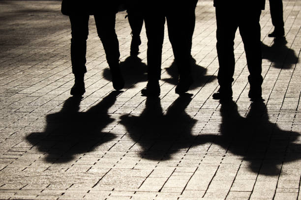 Silhouettes and shadows of people on the street Crowd walking down on sidewalk, concept of strangers, crime, society, epidemic, population gang stock pictures, royalty-free photos & images