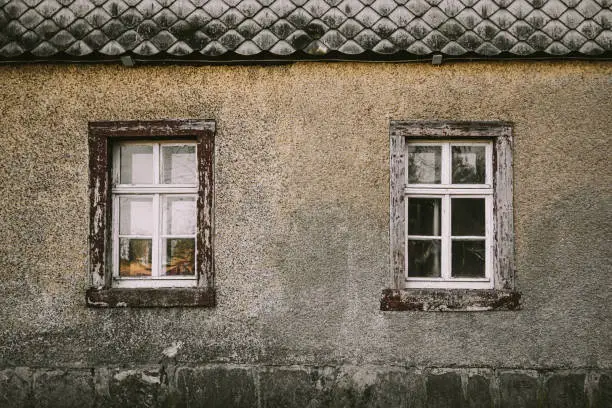 Old house grey facade with white wooden windows and dark tiled roof. Full frame image