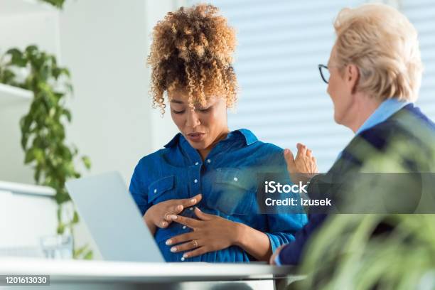 Elderly Colleague Talking To Pregnant Professional Stock Photo - Download Image Now - 35-39 Years, 70-79 Years, Active Seniors