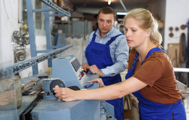 istock Woman with male assistant working on glass beveling machine 1201613050