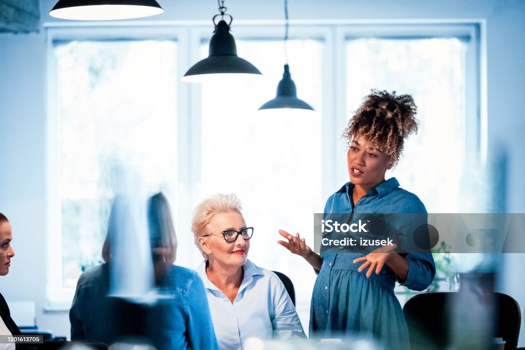 Pregnant owner gesturing and talking to colleagues Pregnant professional gesturing while talking with colleagues. Businesswomen are working together in office. They are discussing new project. Pregnant Stock Photo