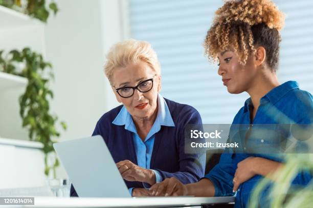 Serious Entrepreneurs Using Laptop At Office Desk Stock Photo - Download Image Now - Pregnant, Advice, Office