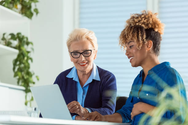 istock Smiling businesswomen discussing over laptop 1201614851