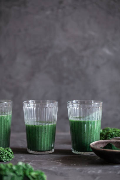 ein gesundes veganes getränk grünkohl smoothie mit spirulina für entgiftung auf dunklem hintergrund - chlorophyll green smoothie smoothie vegetable stock-fotos und bilder