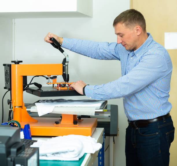 istock Man using a serigraph press to print a shirt in a workshop 1201615392