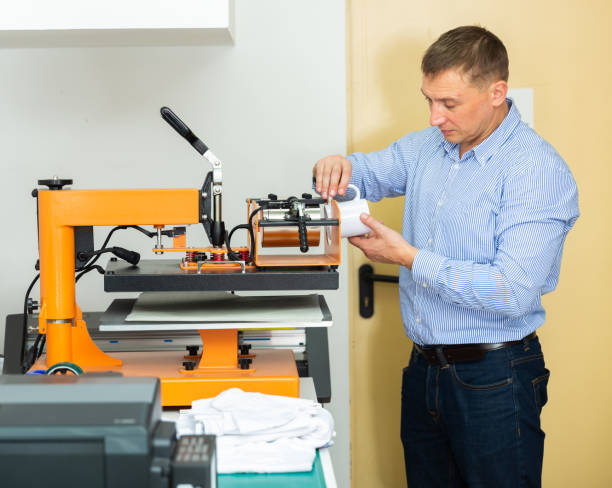 istock Man uses machine to print on ceramic mug 1201615400