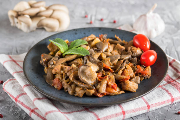 istock Fried oyster mushrooms with tomatoes on gray concrete background. side view, close up 1201616184