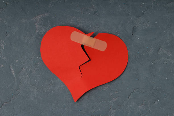 istock Broken heart and glued together with a band-aid. concrete background 1201616299