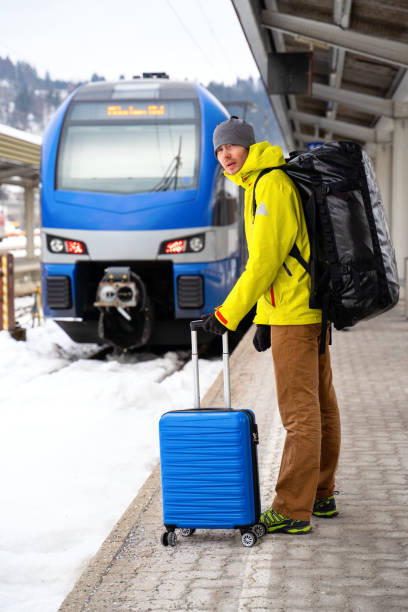istock Tourist looking at camera with blue suitcase at station waiting for train 1201616649