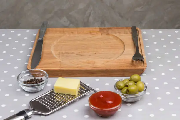 Photo of Homemade food. Serving board knife and fork, olives cheese grater