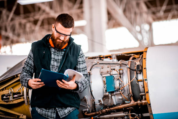 istock Aircraft technician going through a manual while performing service in a maintenance hangar 1201616922