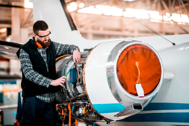 istock Aircraft mechanic trying to fix a problem on a jet engine in a maintenance hangar 1201618193