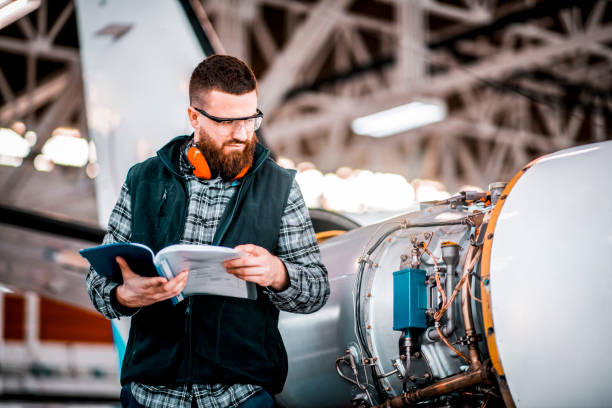 istock Aircraft technician going through schematics while performing service in a maintenance hangar 1201618368