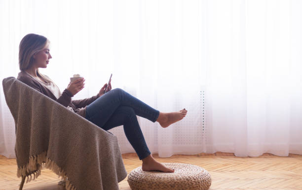 istock Woman enjoying marshmallow cocoa and browsing on phone 1201618383