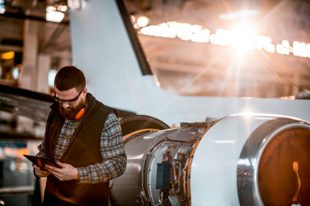 istock Aircraft engineer in a hangar holding a digital tablet while repairing and maintaining an airplane jet engine 1201618592