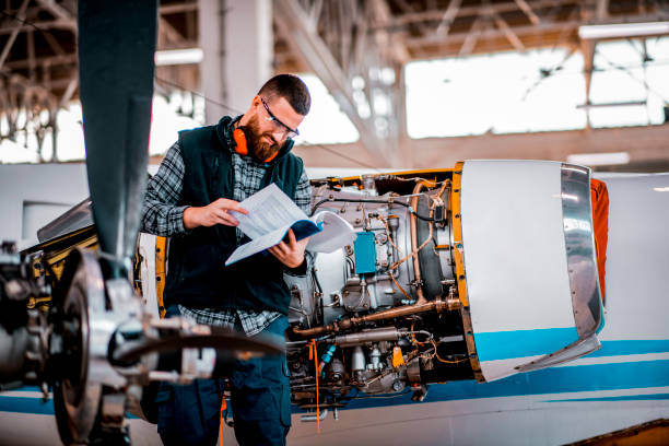 istock Aircraft engineer reading a maintenance instructions in an airplane hangar while working on an airplane 1201618593