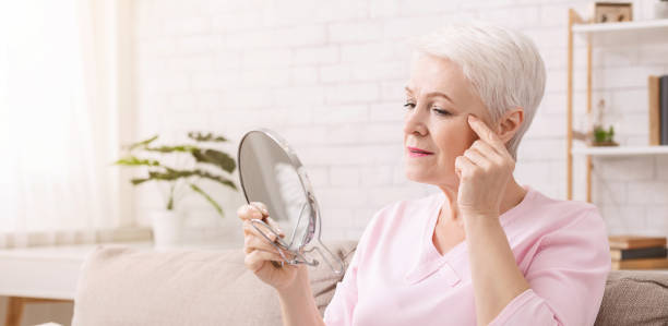 istock Senior lady examining her face skin about wrinkles 1201619641