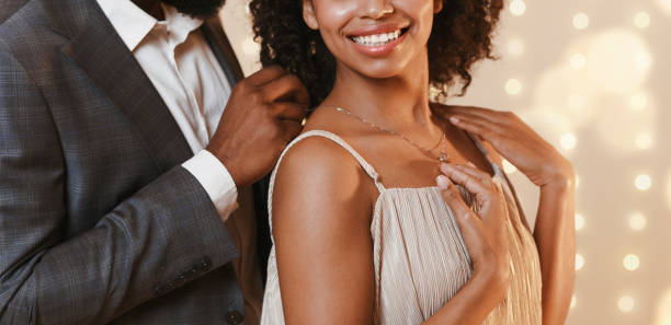 Cropped of african man giving woman beautiful golden chain Cropped of african american man giving woman beautiful golden chain, celebrating anniversary together, panorama gem jewelry gold glamour stock pictures, royalty-free photos & images