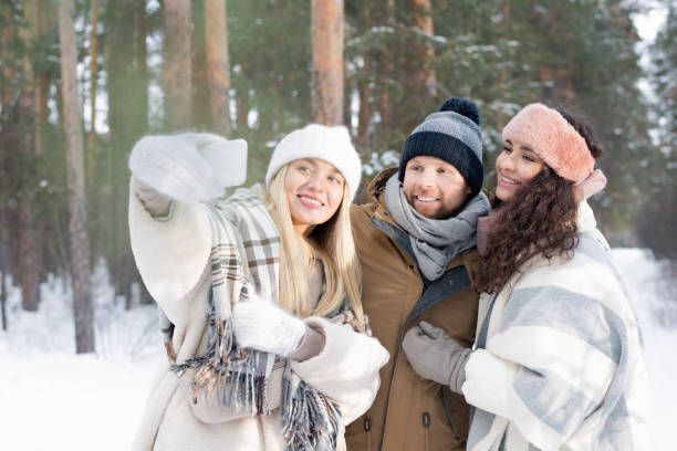 istock Three cheerful and affectionate friends looking at smartphone camera with smiles 1201619996