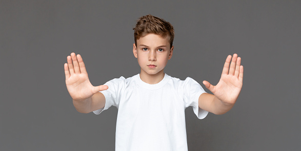 Restriction, prohibition and children concept. Teenage boy making stop gesture over grey background, panorama