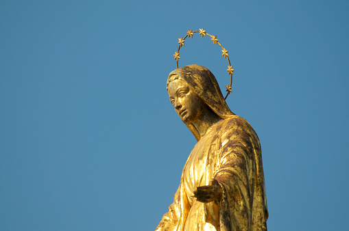 Close up view of the golden Madonnina (Madonna - Immacolata) statue against the blue sky located at the port of Luino in Lombardy, Italy