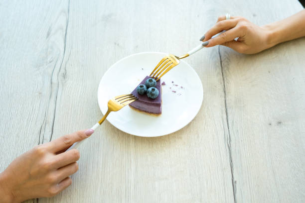 Hands of two young females with forks taking piece of appetizing dessert