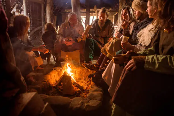 A family group of viking villagers having a fun meeting in a warm settlement hall