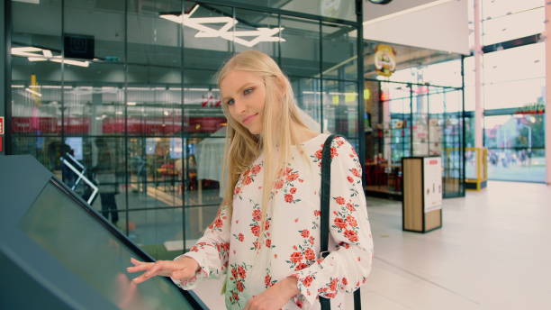 istock Young female looking for right direction on navigation board in modern mall 1201622879