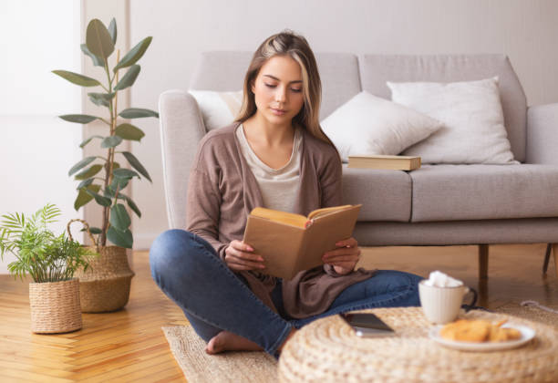 istock Peaceful young lady reading book. enjoying coffee on floor 1201625859