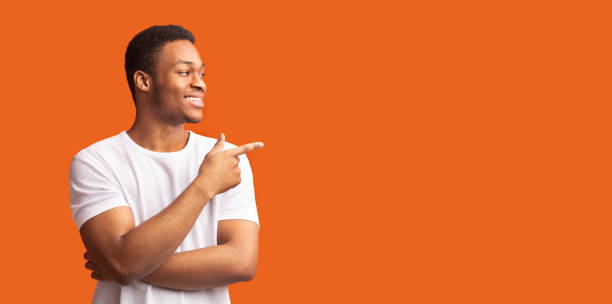 istock Young black man pointing at copy space with thumb up 1201626680