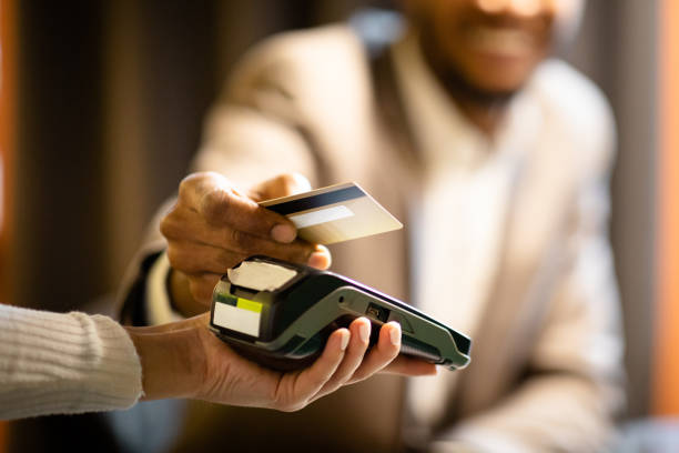 Afro businessman giving credit card to barman NFC Technology. Close up of black manager smiling, giving credit card to waitress paying with gold credit card in cafe checkout photos stock pictures, royalty-free photos & images