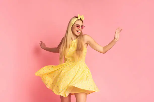 Photo of Cheerful woman dancing over pink studio wall