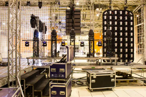 Spotlight devices on a truss. Line array speakers. Big led screen. Flight cases. Installation of professional stage, sound, light and video equipment for a concert.