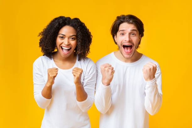 istock Cheeful mixed-race couple celebrating success, raising hands with excitement 1201632479