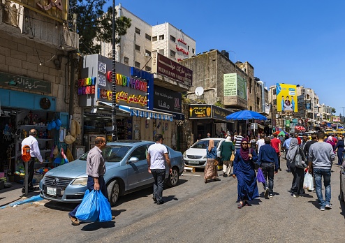 Ramallah, Palestine, May 4, 2019: View of a street in Ramallah on a sunny afternoon. Many local people walk on the road and sidewalks and shop.