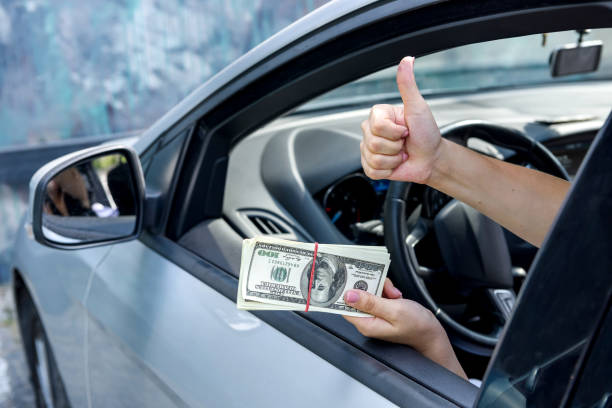 Bribe concept. Female hands giving dollar bundle inside car close up Bribe concept. Female hands giving dollar bundle inside car close up cash for cars stock pictures, royalty-free photos & images