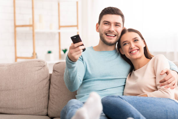 Couple Watching TV Relaxing Sitting On Sofa At Home Weekend. Happy Couple Watching TV Relaxing Sitting On Sofa At Home. Selective Focus, Copy Space cable tv stock pictures, royalty-free photos & images