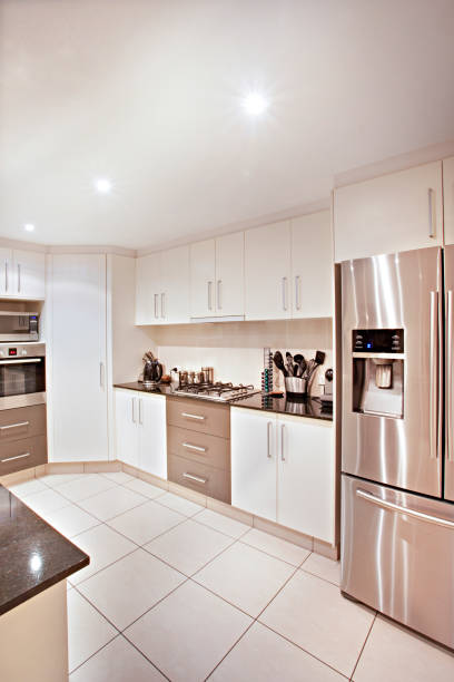 Vertical photograph of a modern kitchen and new tiles Front side of cooking room with cupboards, kitchen design including facilities, latest tools near oven, sink is attached to pantry, ceramic items on table. australia house home interior housing development stock pictures, royalty-free photos & images