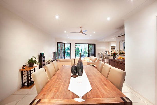 Wooden dining table near living area Wooden dining table near living area, comfortable furnitures with designs, walls are white color, pillows on chairs, inside rooms of a apartment. australia house home interior housing development stock pictures, royalty-free photos & images