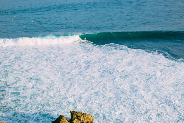 istock Aerial view with surfers and wave in tropical blue ocean. 1201638844
