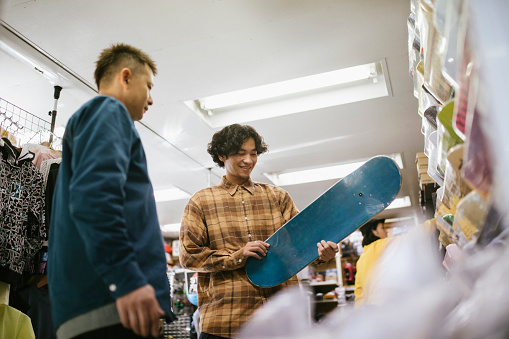 Young man choosing skateboard deck at a skateboard store.