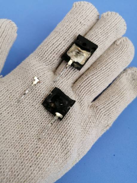 istock Parts of a broken transistor with a contact on a gloved hand 1201649266