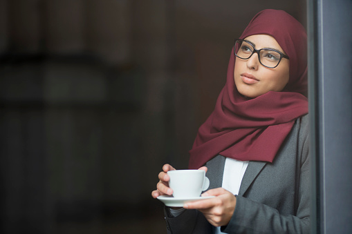 Arabian business woman with hijab enjoying her coffee.