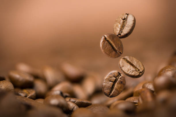 istock Brown roasted coffee beans falling on pile.Represent breakfast, energy, freshness or great aroma,Flying on stack of seed and dark background with copy space, close-up 1201650693
